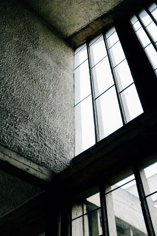 Free From below big rectangular shaped windows on concrete buildings with uneven walls and ceiling in daylight Stock Photo