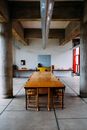 Interior of spacious light refectory with long dining table under ceiling with massive wooden beams