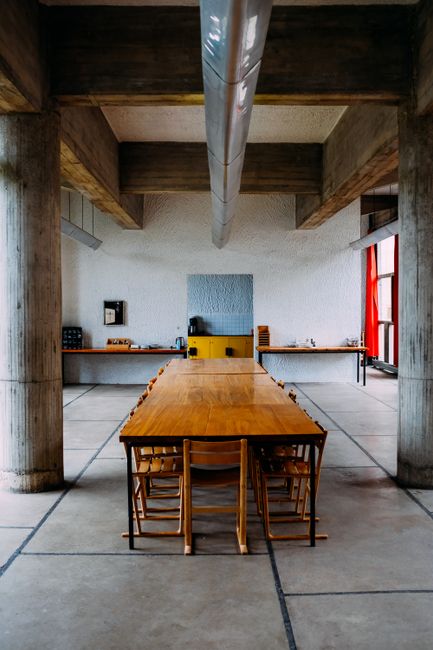 Interior of spacious light refectory with long dining table under ceiling with massive wooden beams