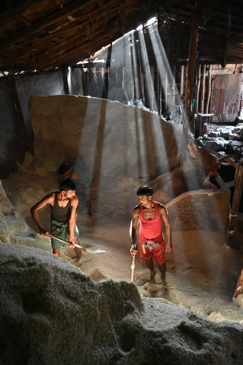 Free Men excavating soil in a sunlit warehouse in Chattogram, Bangladesh. Stock Photo