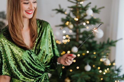 Smiling Woman Holding a Sparkler During Christmas Time 