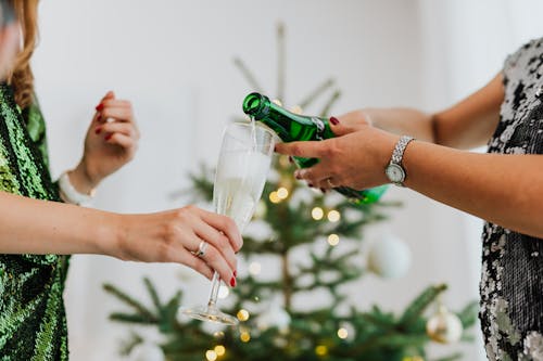 Close-Up Photo of Person Pouring a Champagne into a Wine Glass