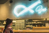 Stylish woman looking on glowing signage in bar