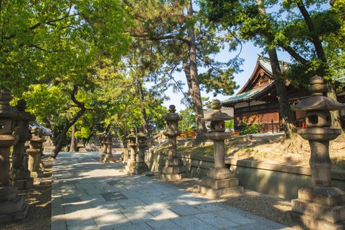 Free Picturesque view of ancient temple territory with stone lanterns and evergreen trees located in Sumiyoshi Grand Shrine Osaka Japan Stock Photo