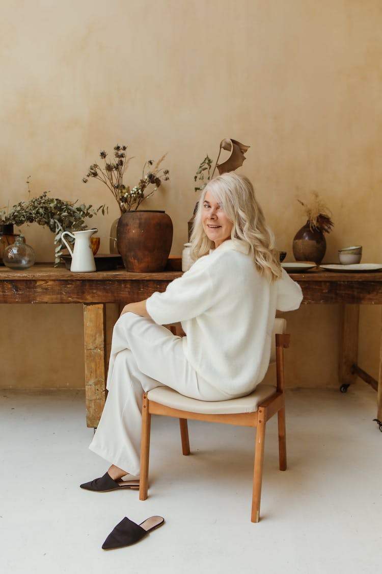 An Elderly Woman Looking Back While Sitting In A Chair