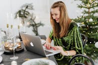圣诞节庆祝活动期间，一位身穿绿色连衣裙的女子微笑着用笔记本电脑工作