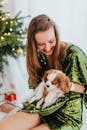 一位穿着节日服装的快乐女人在圣诞树旁抱着一只小狗