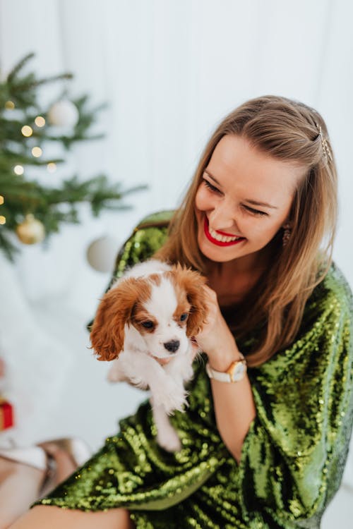 Smiling Woman in Green Dress Holding Her Cute Puppy