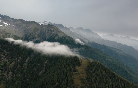 Aerial view of a mountain range with misty clouds and lush forests, capturing the essence of untouched nature.