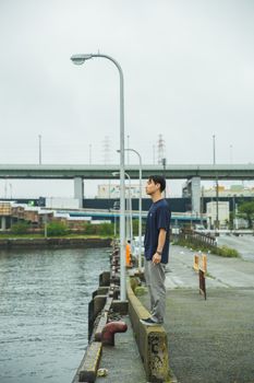 一名年轻人若有所思地站在大阪的河边