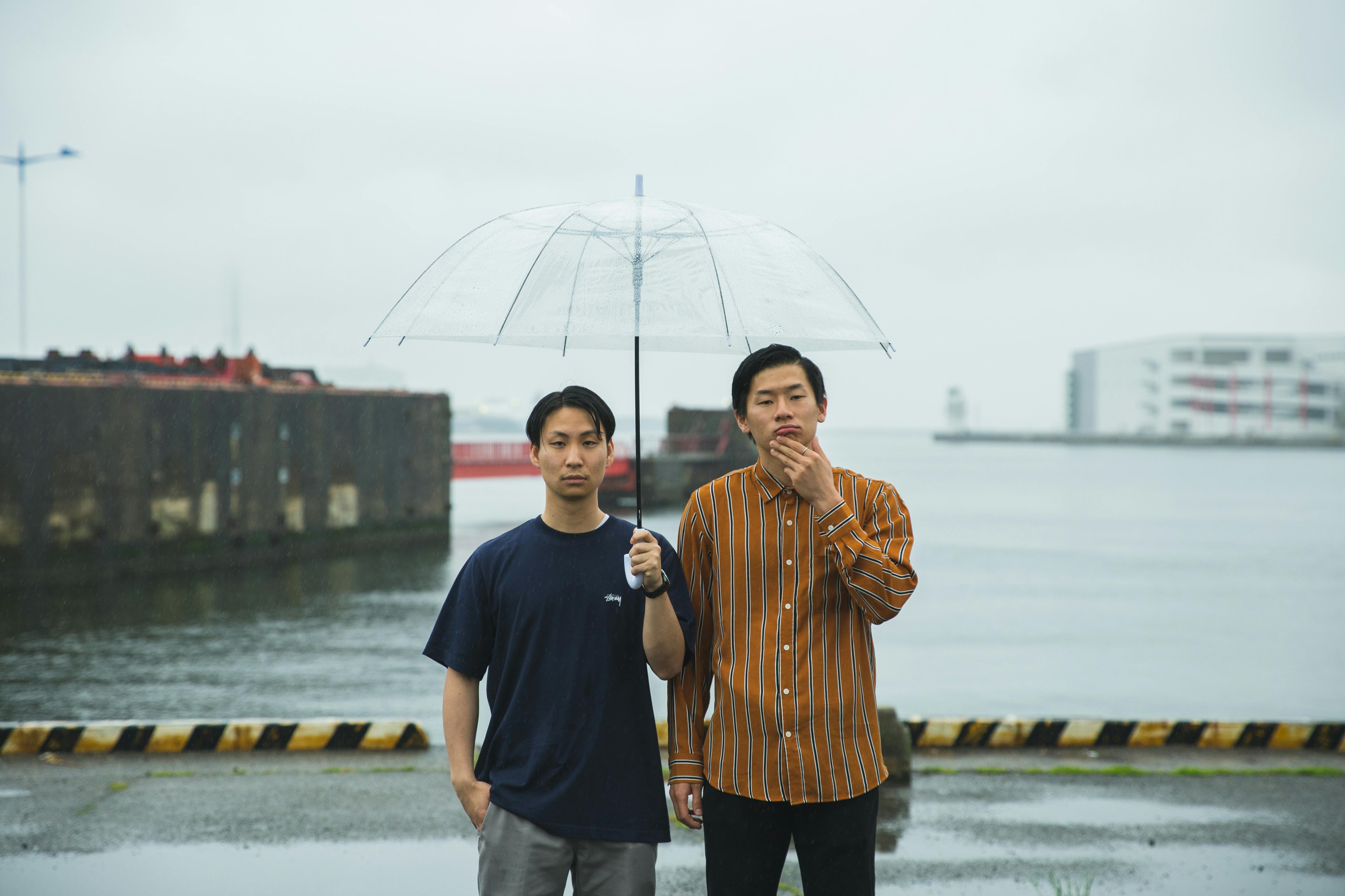 阴沉的日子里，两名男子撑着伞站在大阪海滨，捕捉到城市宁静平和的气息