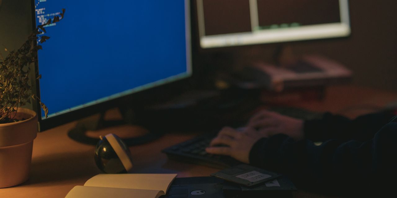 Individual programming in a dimly lit room with dual monitors.