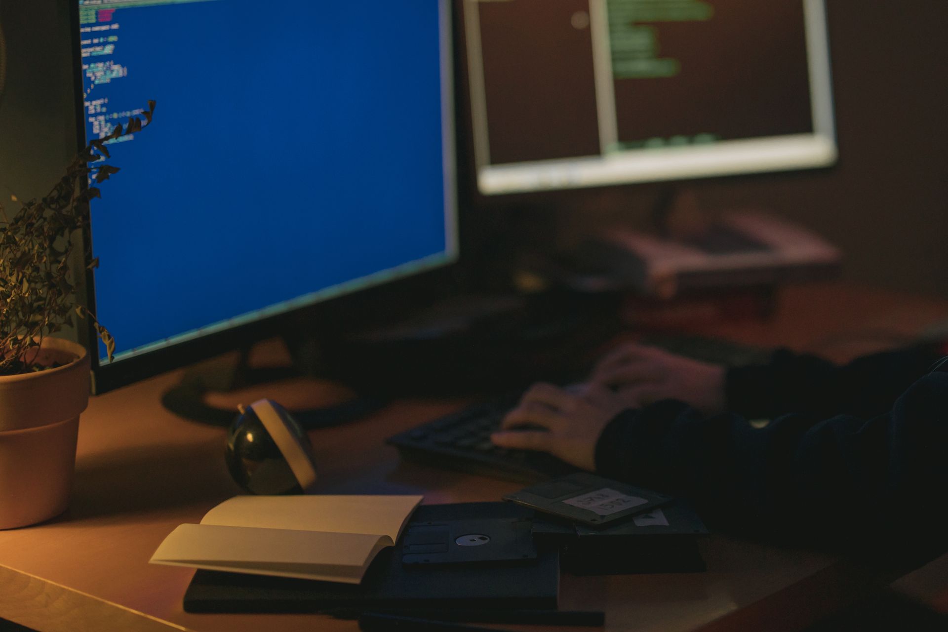 A developer's keyboard and a screen showing code on a dark desk