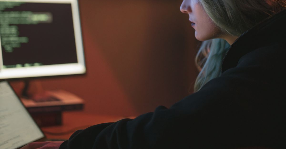 person looking thoughtfully at a laptop screen with code visible