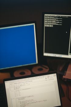 A multi-screen workstation showcasing coding on monitors and a laptop.