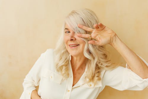 Smiling Elderly Woman Doing a Peace Sign while Looking at Camera