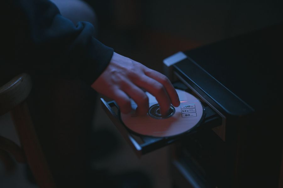 A hand inserting a CD into a computer's optical drive