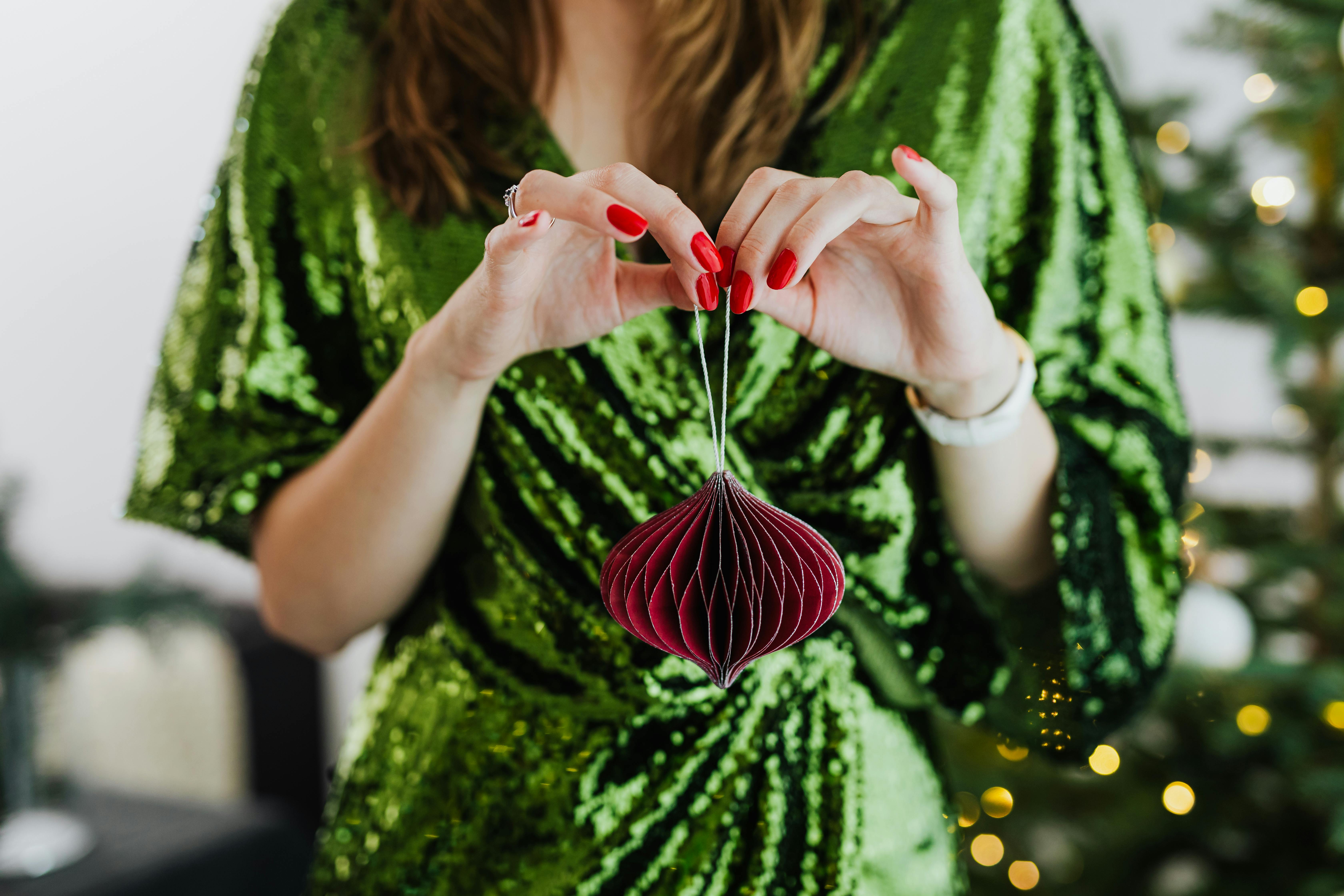 一位身着绿色亮片连衣裙的优雅女士，手持红色装饰品，洋溢着喜庆的节日气氛