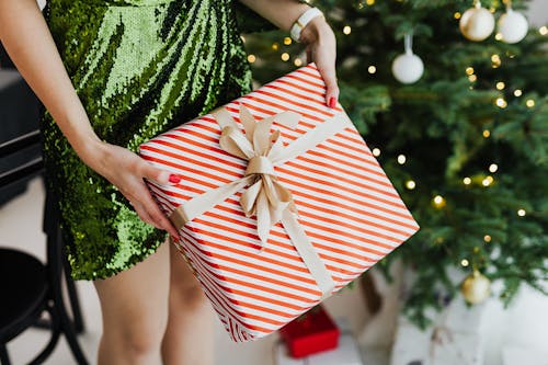 Person in Green Glittery Dress Holding a Gift Box