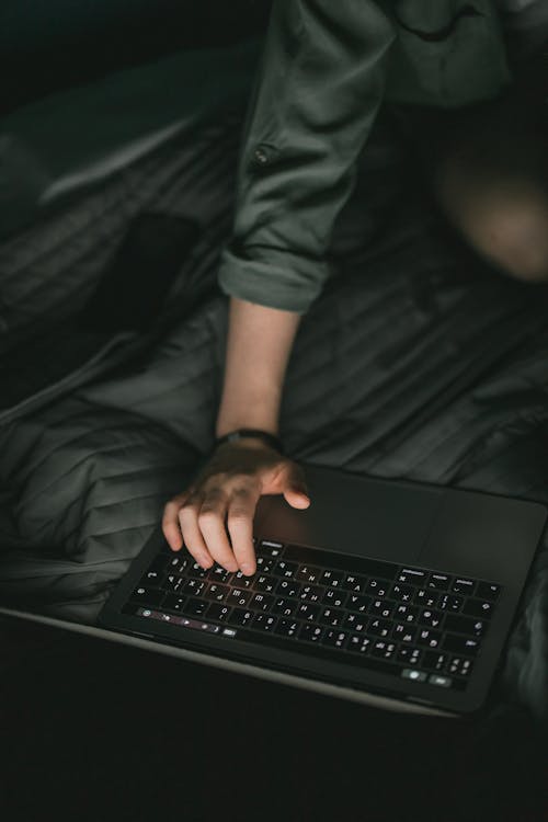 A Person Using a Laptop on the Bed