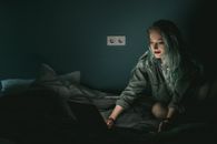 在光线昏暗的卧室里，一位白人妇女正使用笔记本电脑，营造出舒适的夜晚氛围