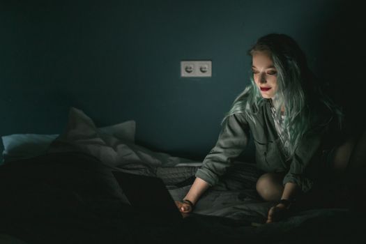 在光线昏暗的卧室里，一位白人妇女正使用笔记本电脑，营造出舒适的夜晚氛围