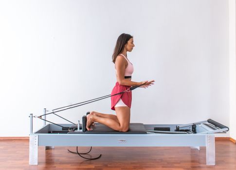 Side View of a Woman in Activewear Doing Pilates Reformer Exercise