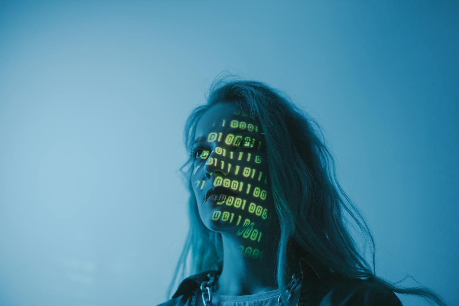 A woman with binary code lights projected on her face, symbolizing technology