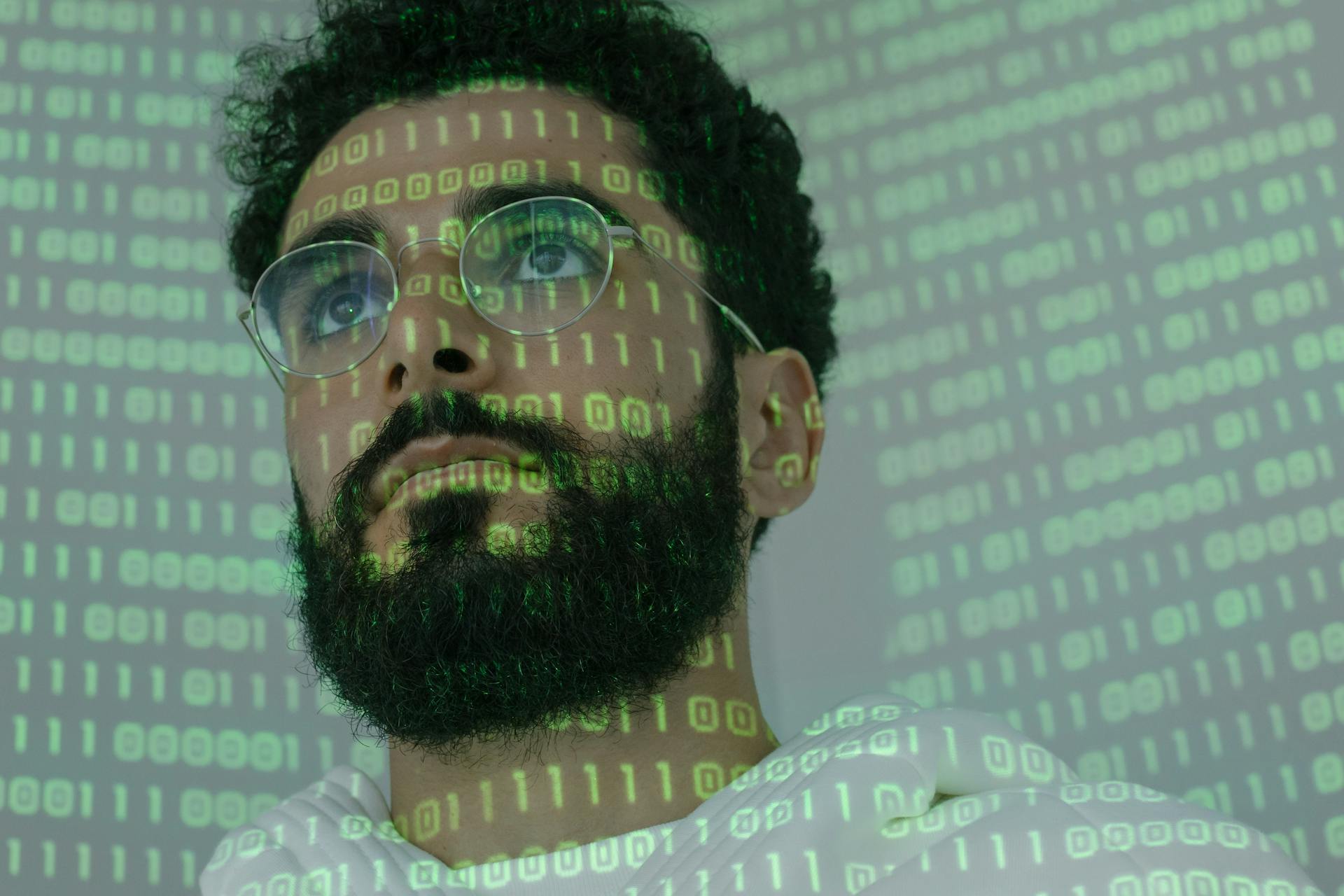 Close-up of a man with glasses and binary code projection, symbolizing cyber security.