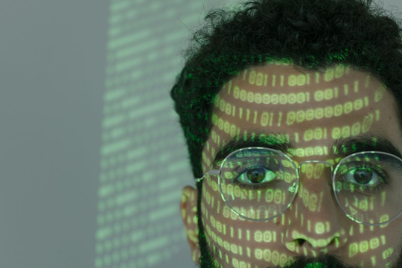 close up of a man with binary code projected on his face symbolizing c