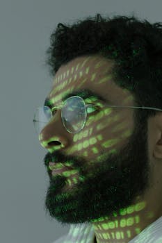 Headshot of a man with green binary code projected on face, symbolizing cybersecurity.