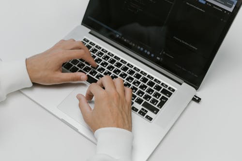 Free Close-up of hands typing on a laptop with a USB device on a white background. Ideal for tech and cybersecurity themes. Stock Photo