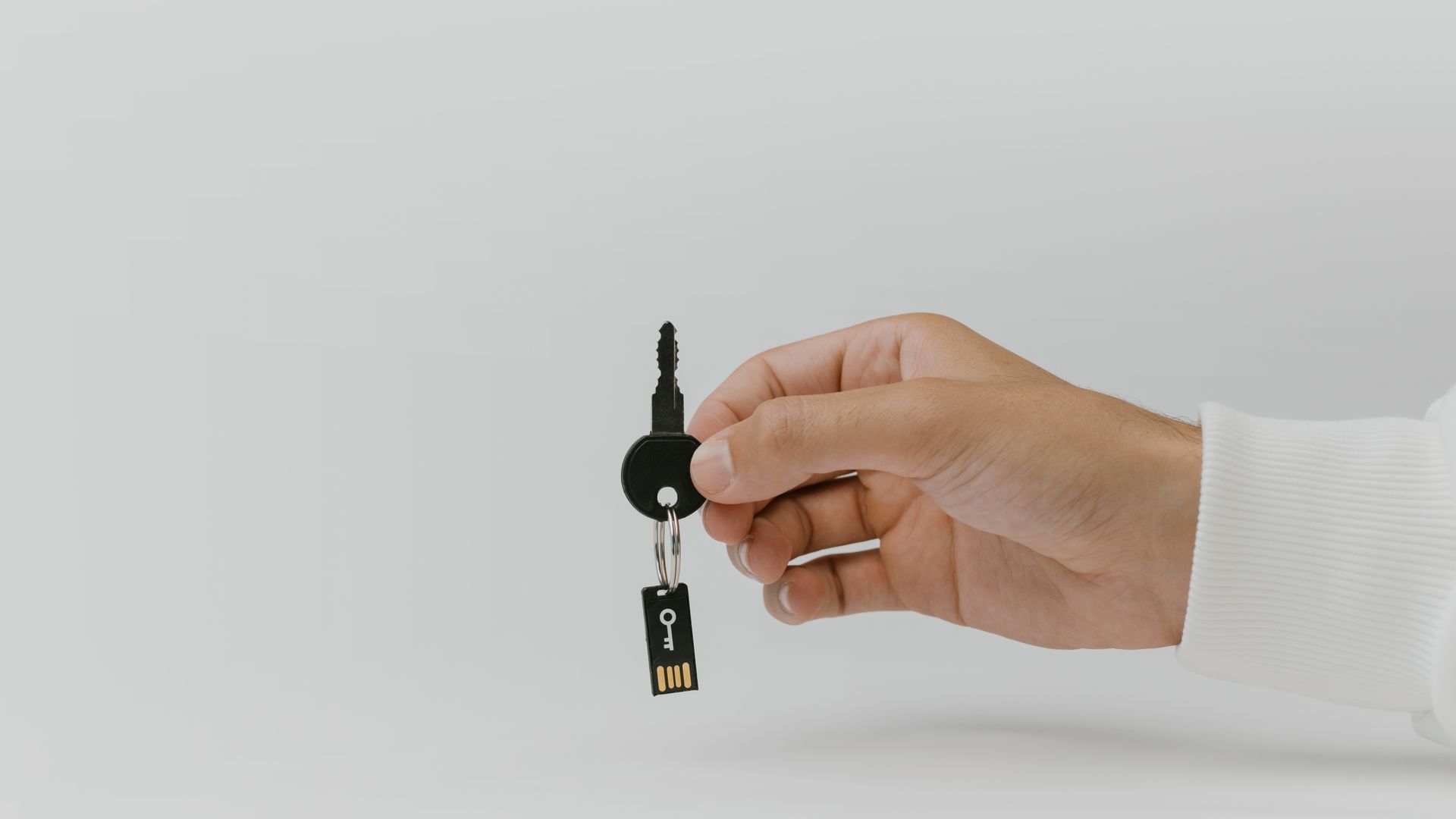 Hand holding keychain with integrated USB flash drive against a plain background — beginners unlocking tips