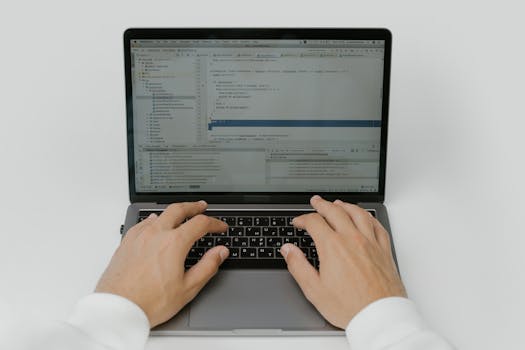Close-up of hands coding on a laptop, showcasing software development in action.