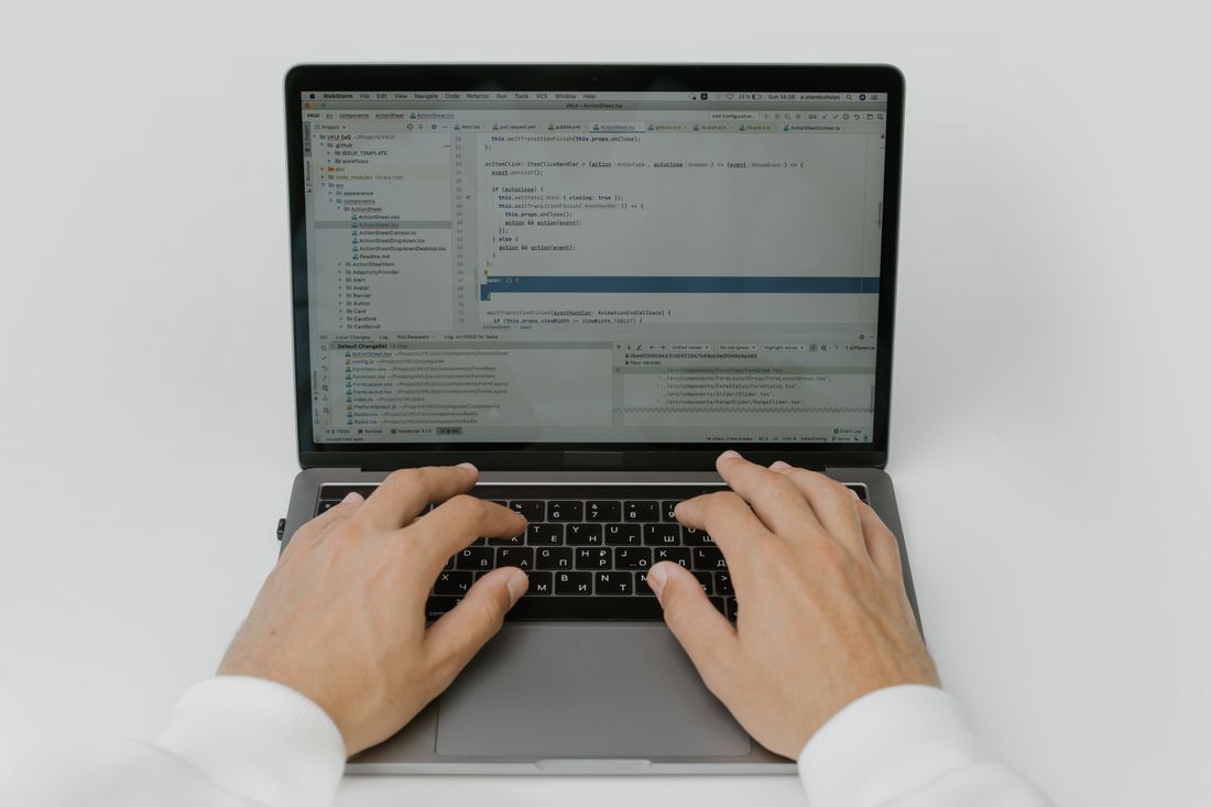Two hands resting on a laptop keyboard seen from above on a white desk