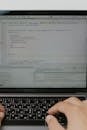 笔记本电脑上输入代码的手部特写，展现了软件开发和编码的过程