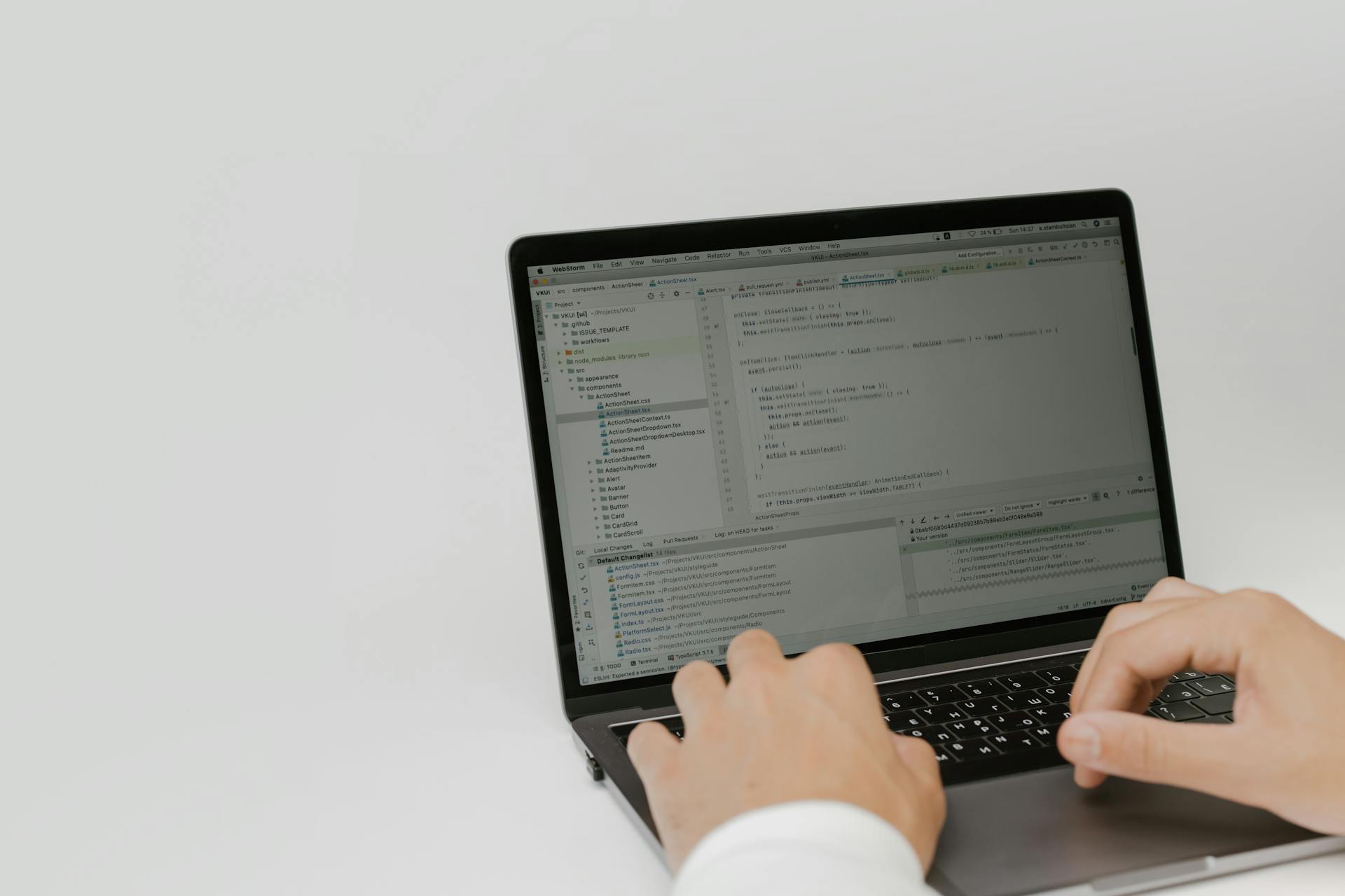 Hands typing code on a laptop in a workspace. Indoor setting focused on software development.