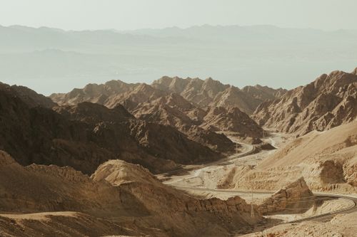 Free Breathtaking view of a rugged desert landscape with winding roads amidst rocky mountains, captured in warm tones. Stock Photo