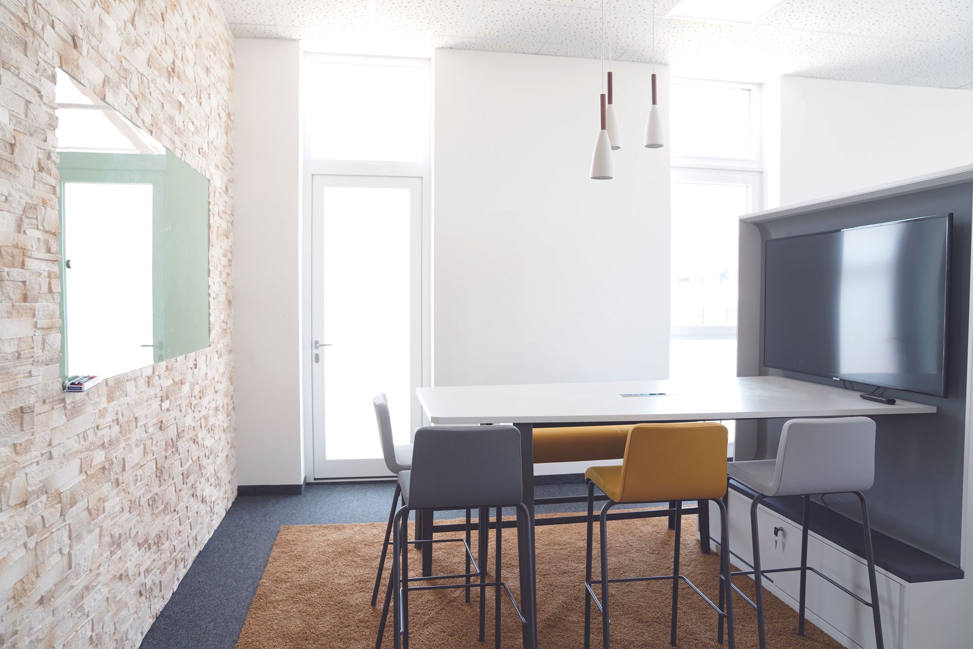 A sleek, minimalist meeting room with modern decor and a large television setup, perfect for presentations.
