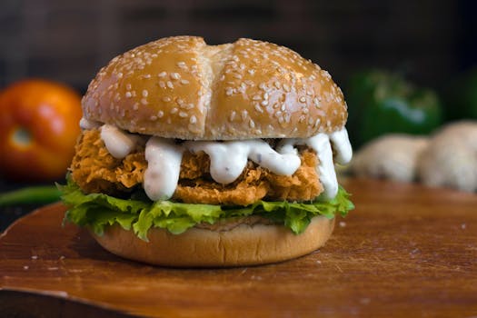 Delicious crispy chicken burger with lettuce and creamy dressing on a sesame bun.