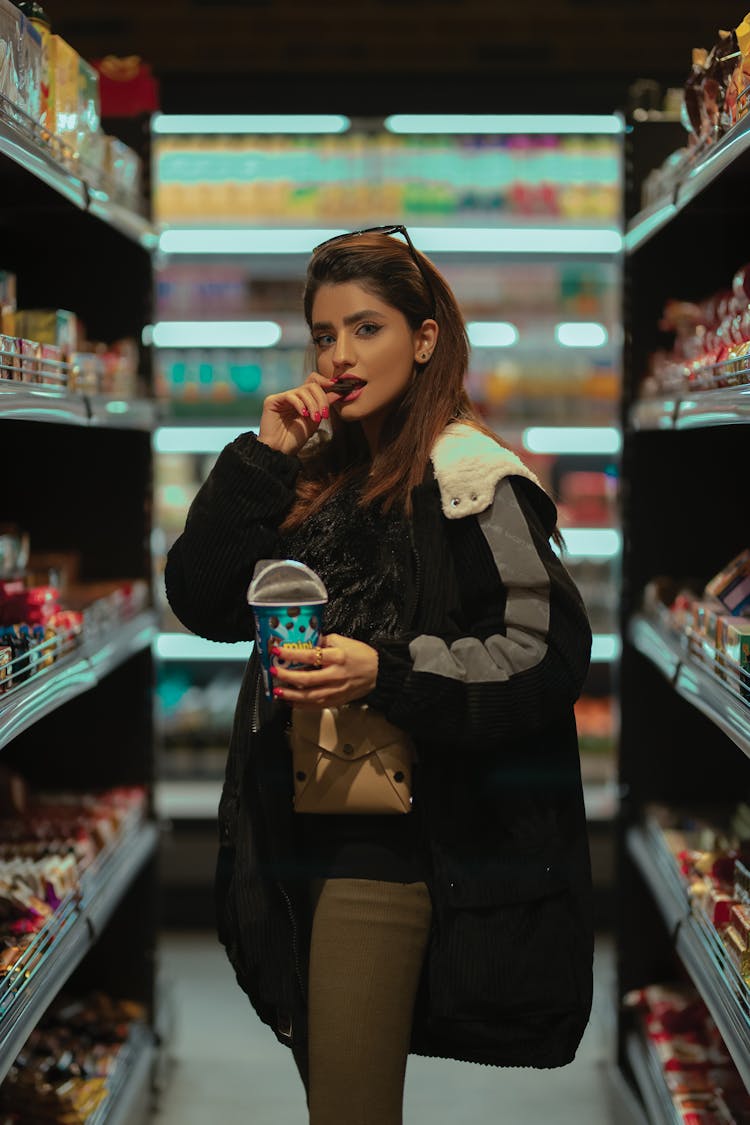 A Woman Eating Cookies Inside The Grocery Store