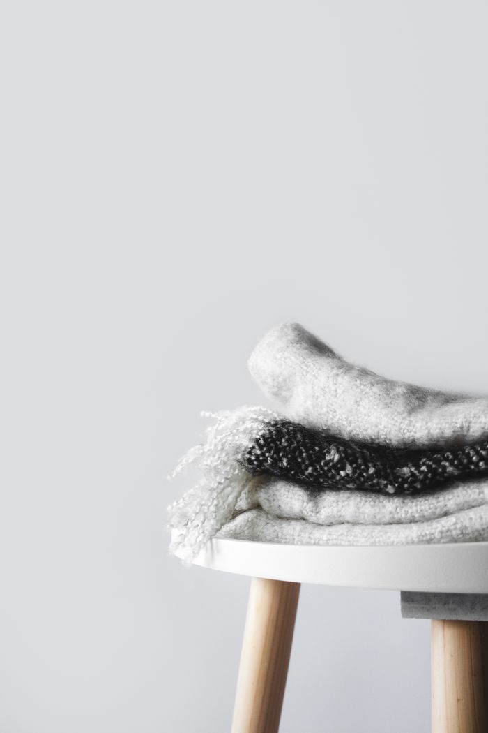 Folded woollen scarves on a round table, photo by Tijana Drndarski on Pexels