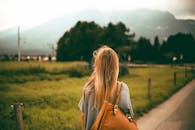 日落时分，一名金发女子背着背包，在风景优美的山地间探索，捕捉到自由与旅行的感觉