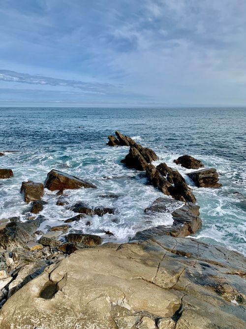 Free Dramatic rocky shoreline with crashing ocean waves under a cloudy sky. Stock Photo