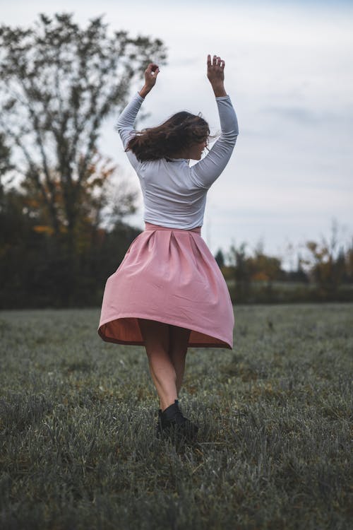 Femme En Chemise à Manches Longues Blanche Et Jupe Rose Debout Sur Le Terrain De L'herbe Verte