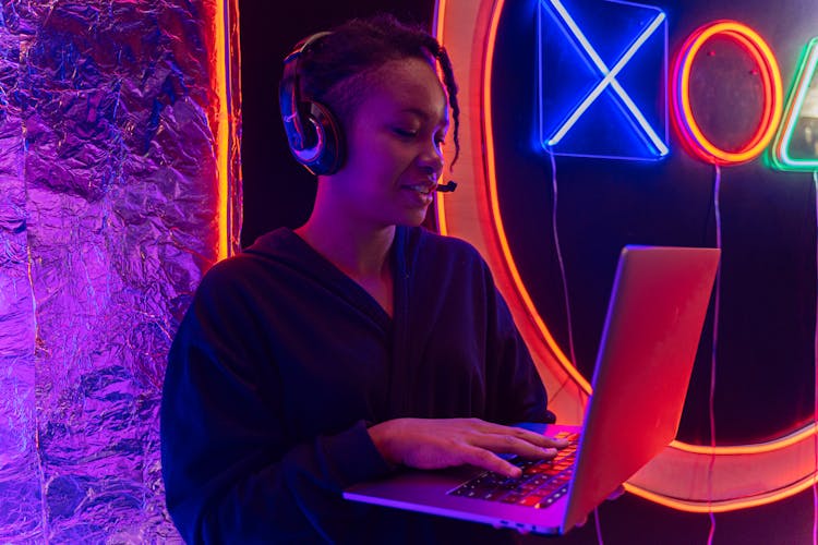 Close-Up Shot Of A Woman Wearing Headphones While Using A Laptop