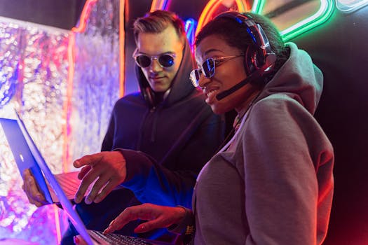 Two tech enthusiasts with laptops and headsets in a vibrant club setting.