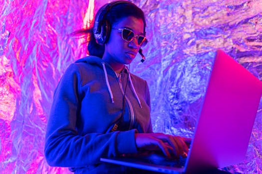 A dynamic DJ wearing sunglasses and a headset, performing with a laptop in a colorful setting.