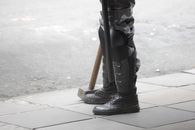 Person Standing on Sidewalk with Truncheon and Hammer