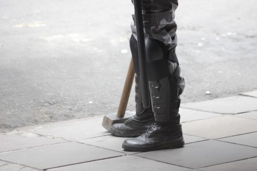 Person Standing on Sidewalk with Truncheon and Hammer